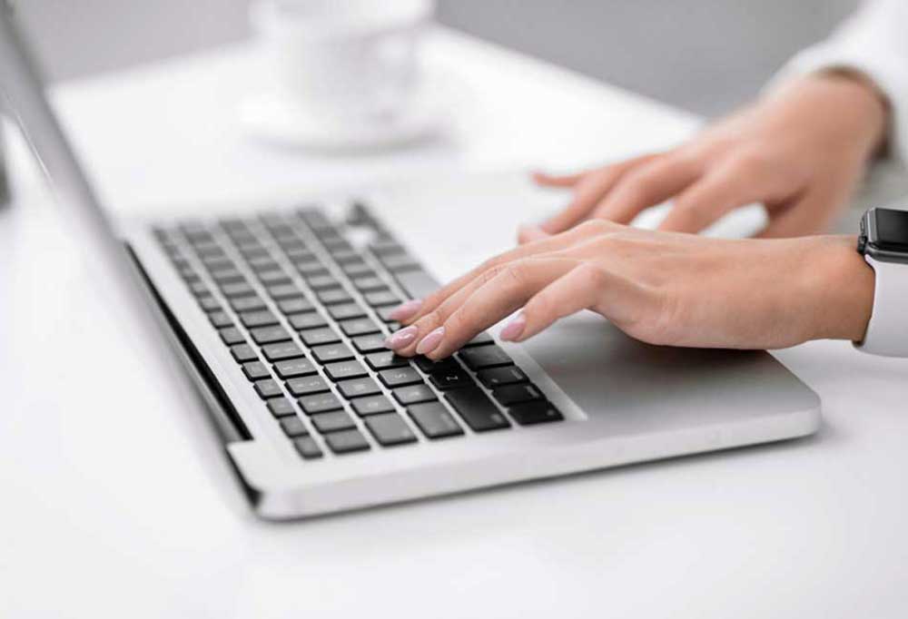 Hands typing on a laptop keyboard